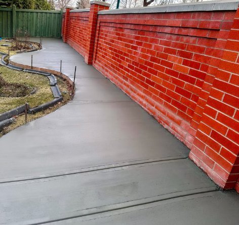 Walkway curving toward a green fence