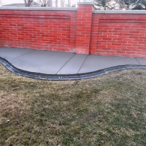 Curved concrete path along a red brick wall